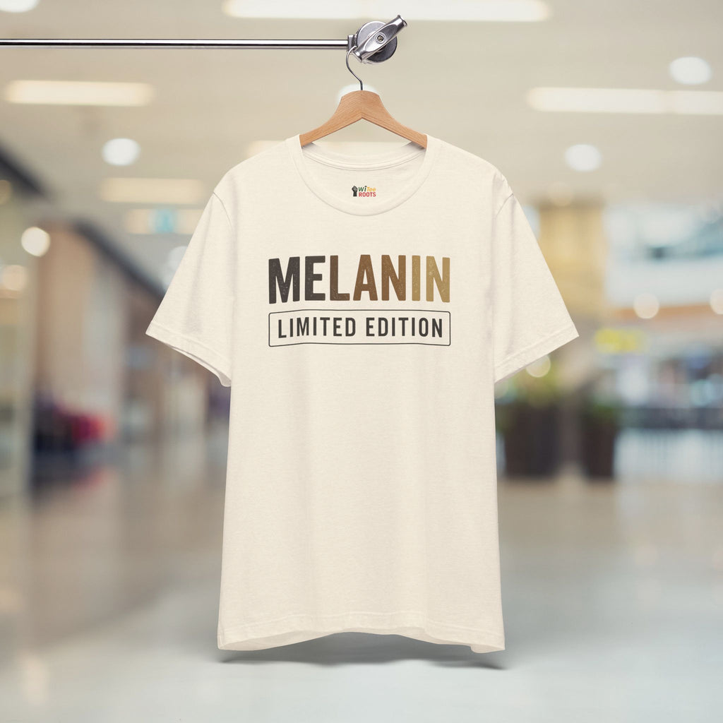 Beige t-shirt with 'MELANIN LIMITED EDITION' text on a hanger in a blurred indoor setting