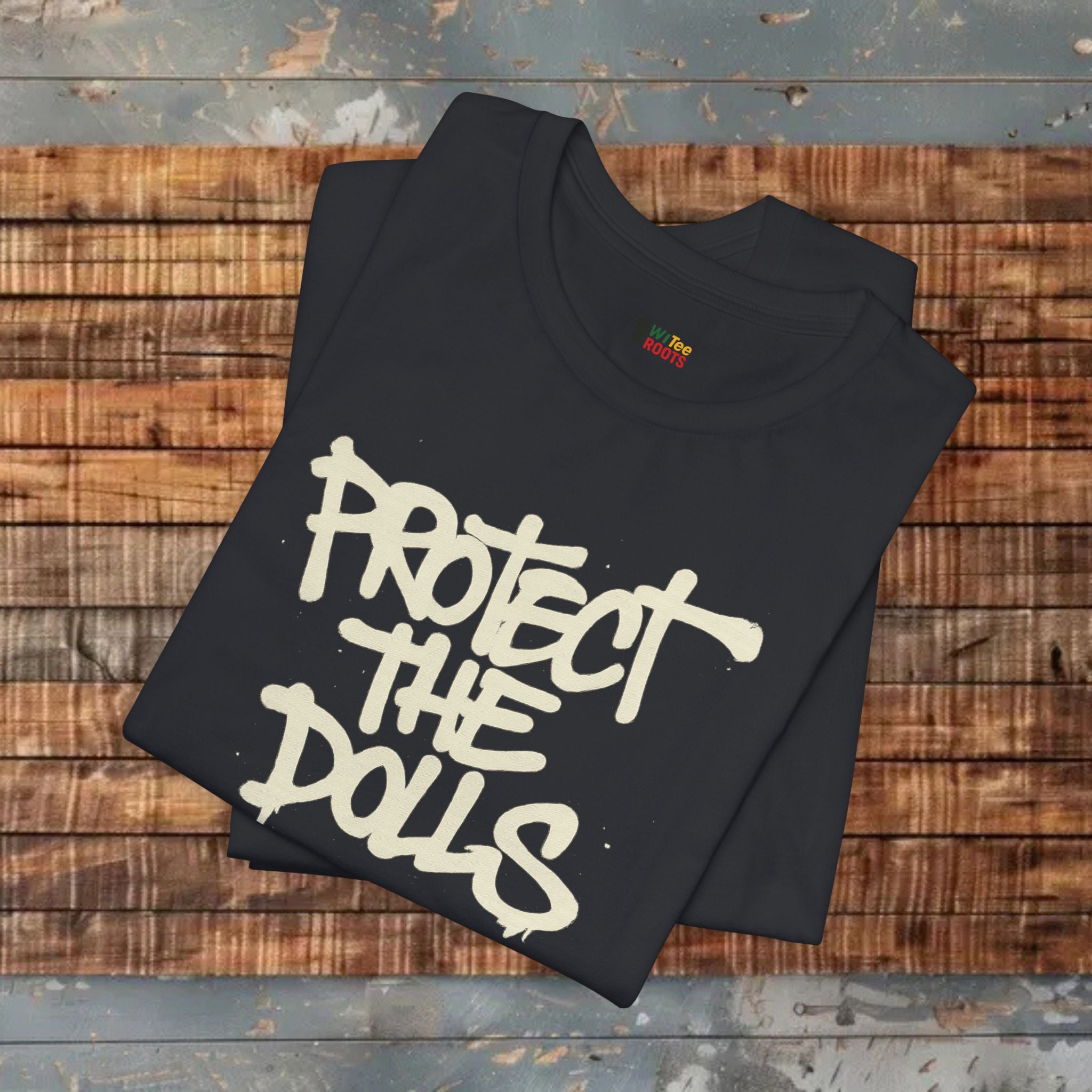 Black t-shirt with 'PROTECT THE DOLLS' text on a wooden surface