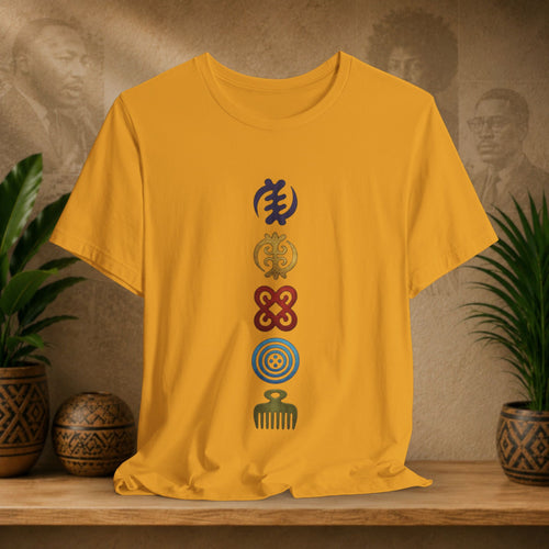 Yellow t-shirt with symbols on a wooden shelf with decorative plants and background.