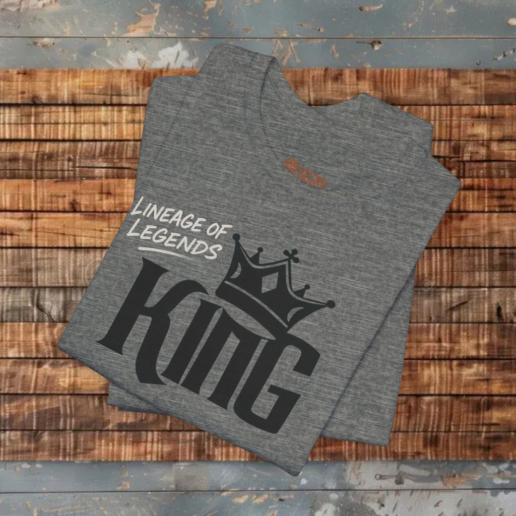 Gray t-shirt with 'Lineage of Legends King' text and crown graphic on a wooden surface