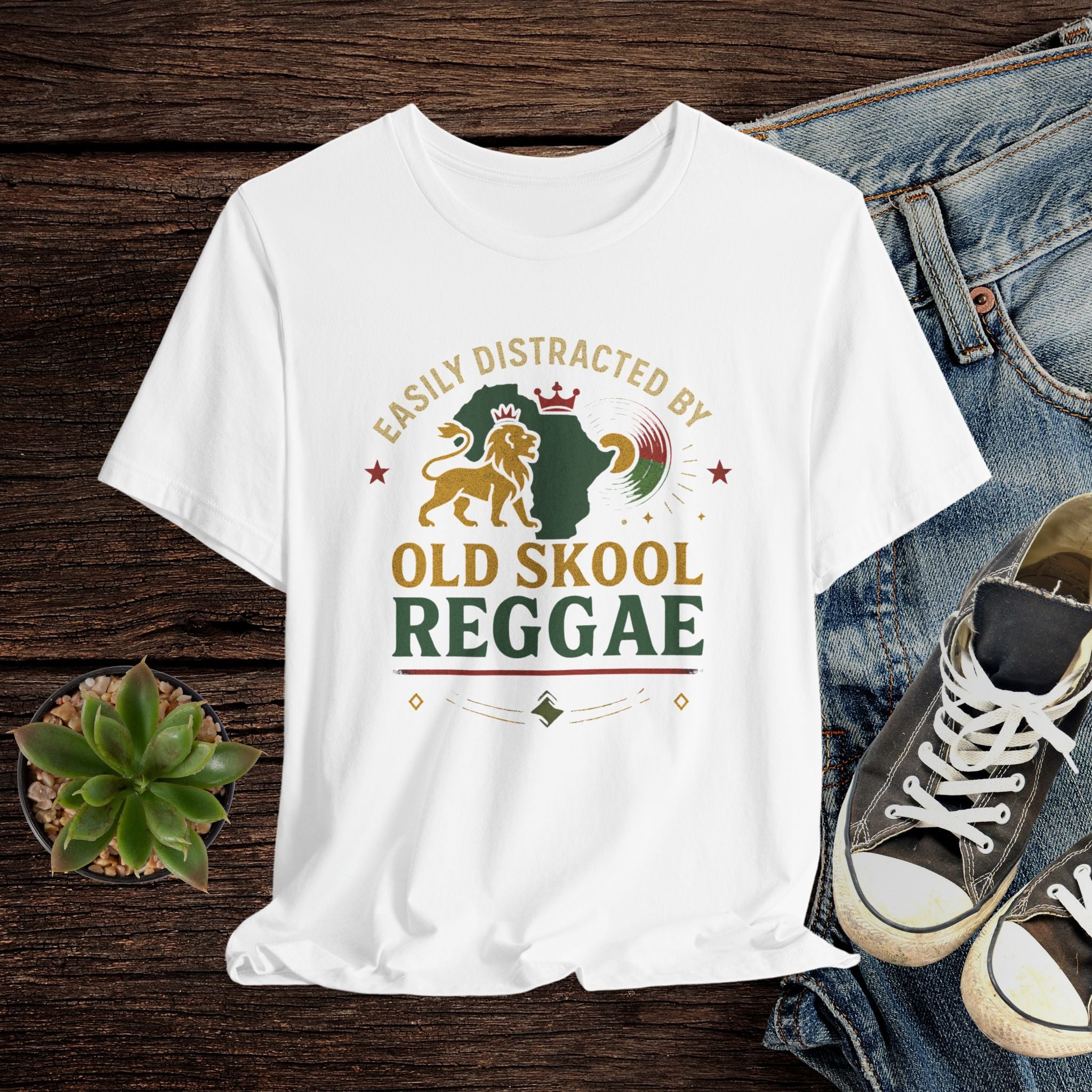 White t-shirt with 'Old Skool Reggae' design on a wooden surface with jeans and sneakers.