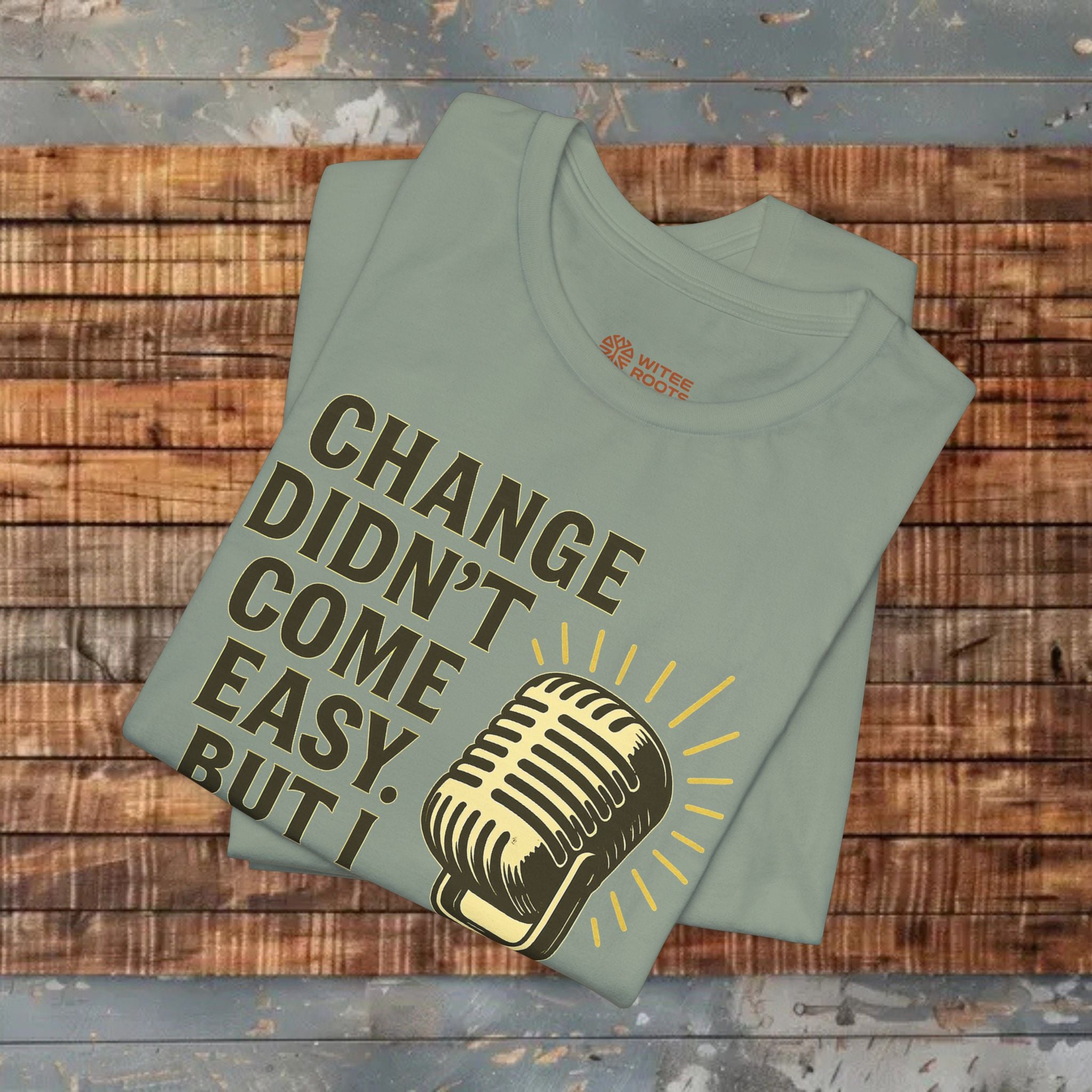 Folded green t-shirt with a microphone graphic and text on a wooden surface
