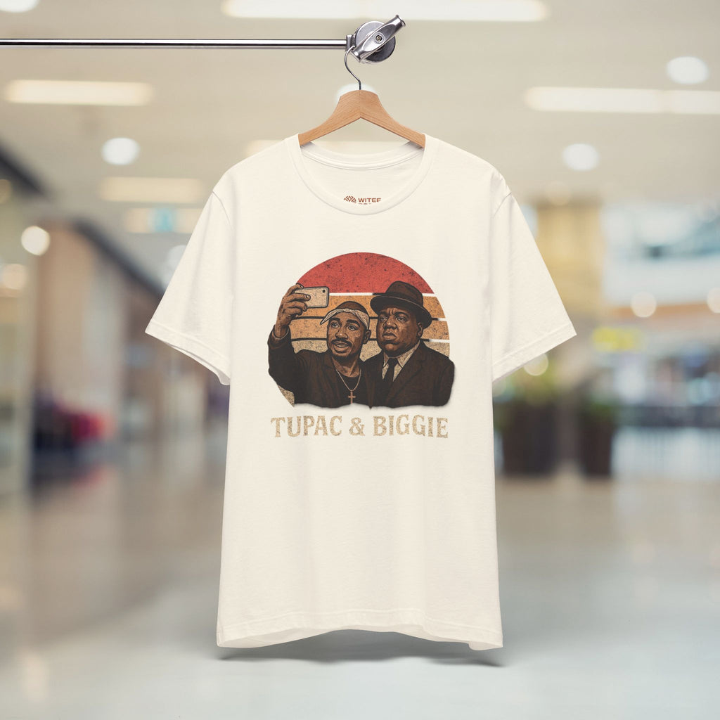 White t-shirt with graphic design of two men and text 'Tupac & Biggie' on a hanger in a store.