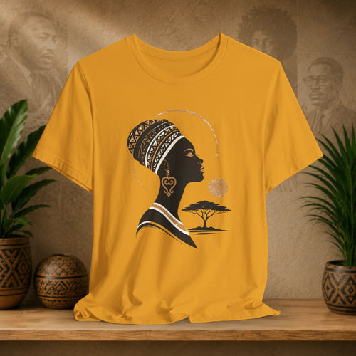 Yellow t-shirt with a black silhouette of a woman with an afro and a tree design on a wooden surface with plants and decorative items.