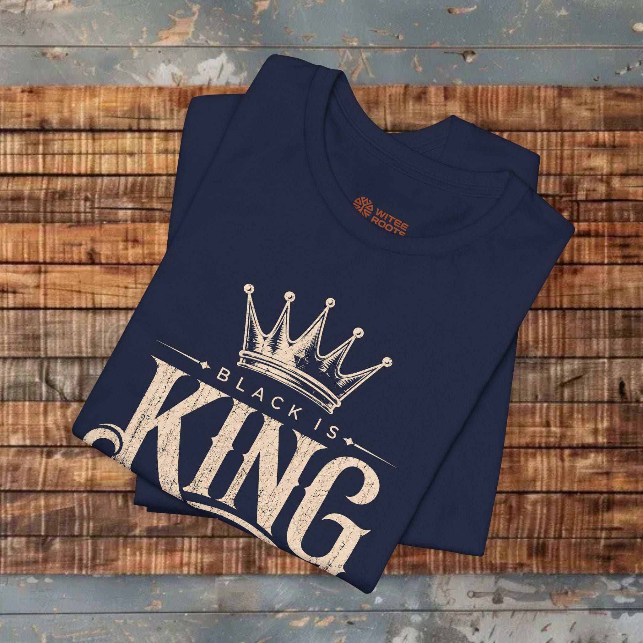 Folded navy blue t-shirt with 'Black is King' design on a wooden surface