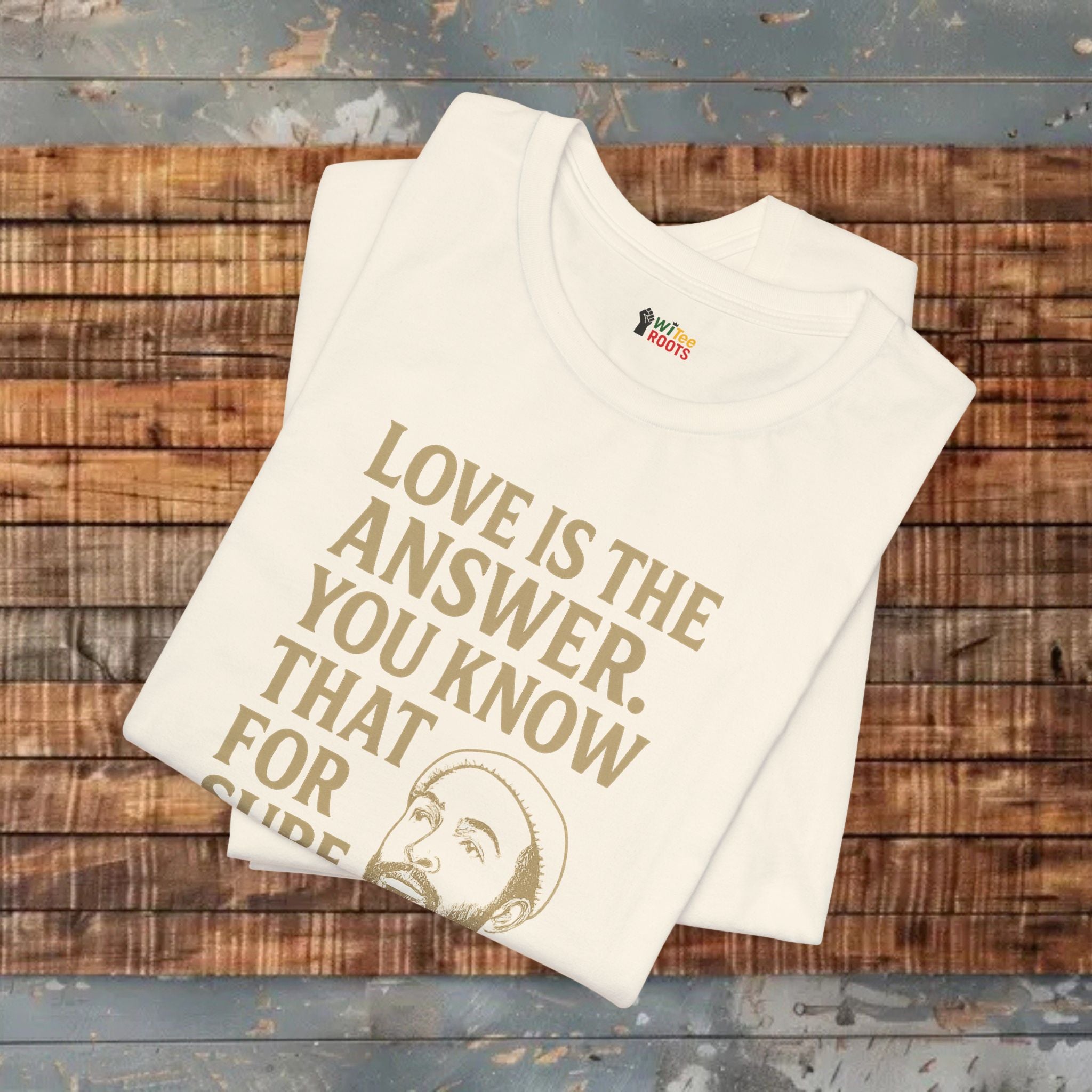 Beige t-shirt with 'Love is the answer. You know that for sure' text on a wooden surface