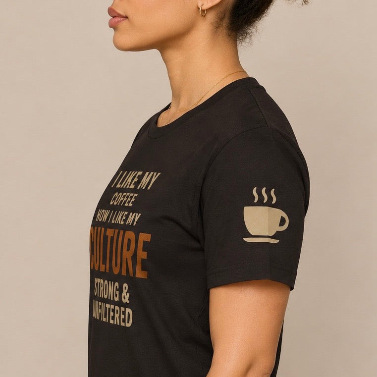 A woman wearing a black short-sleeve graphic t-shirt with beige text and a coffee cup illustration on the sleeve, shown in a side profile against a neutral beige background.