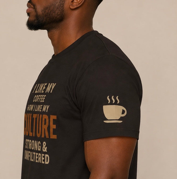 A man wearing a black short-sleeve t-shirt with a coffee-themed graphic print in beige and brown. The shirt features a coffee cup icon on the left sleeve and text on the right chest that reads 'I LIKE MY COFFEE HOW I LIKE MY CULTURE STRONG & UNFILTERED'.