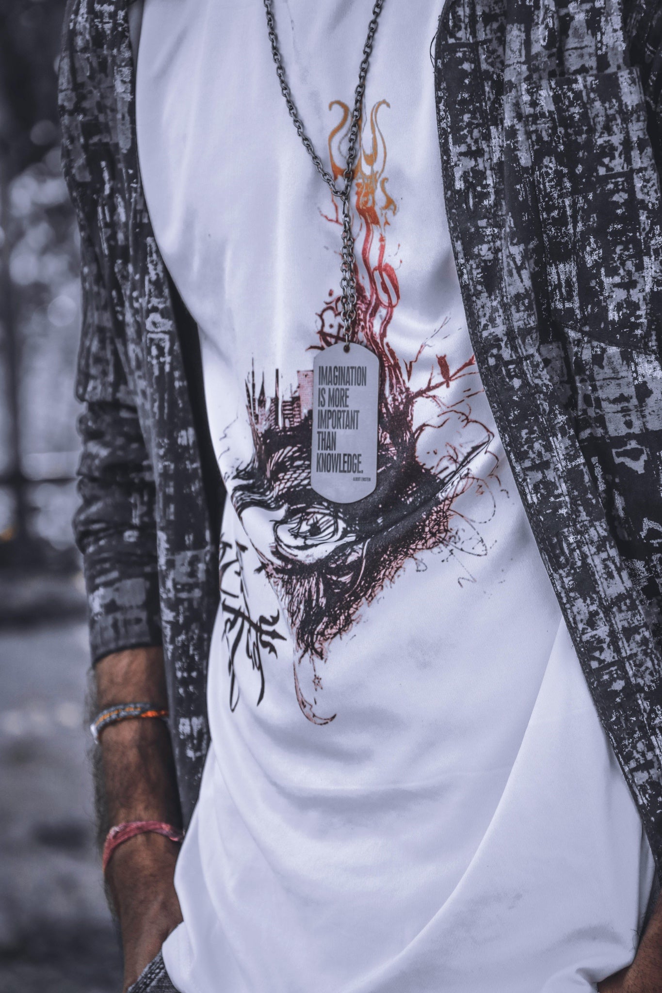 Person wearing a white t-shirt with a graphic design and a necklace.